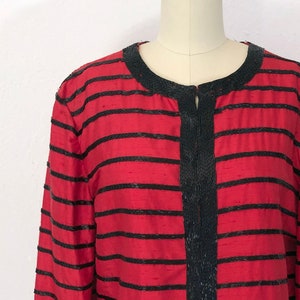 May include: A red and black striped jacket with a beaded trim. The jacket is on a dress form.