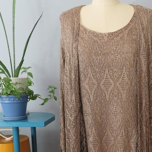 May include: A gold and brown sequined dress with black fringe. The dress is on a mannequin and has a scoop neck and long sleeves.