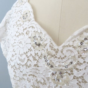 May include: White lace fabric with a V-neckline and beaded embellishments.