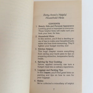 Peut inclure: Page ouverte d'un livre avec le titre "Betty-Anne's Helpful Household Hints" et une table des mati&egrave;res. Les sujets incluent les aides &agrave; la beaut&eacute;, les conseils m&eacute;nagers, les aides de cuisine, la cuisine, les bagages et les taches. Le num&eacute;ro de page est 7.