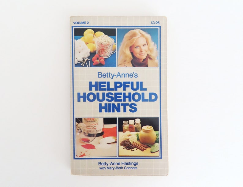 Peut inclure: Un livre vintage intitul&eacute; "Betty-Anne's Helpful Household Hints, Volume 2". La couverture pr&eacute;sente un portrait de femme et des images d'objets m&eacute;nagers. Le livre a une bordure bleue et un fond quadrill&eacute;.
