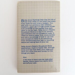 Peut inclure: Dos de livre vintage, "Betty-Anne's Helpful Household Hints". La couverture grise clair &agrave; motif quadrill&eacute; pr&eacute;sente du texte bleu. Le texte d&eacute;crit les astuces de l'ouvrage pour &eacute;conomiser &agrave; la maison.