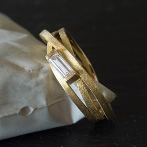 Modern engagement ring with three gold bands and baguette diamond. Perfect minimal bridal ring.