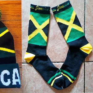 May include: A set of three Jamaican themed accessories: a black, green, and yellow beanie with a pom-pom, a pair of black socks with a green, yellow, and black Jamaican flag design, and a black, green, and yellow belt.