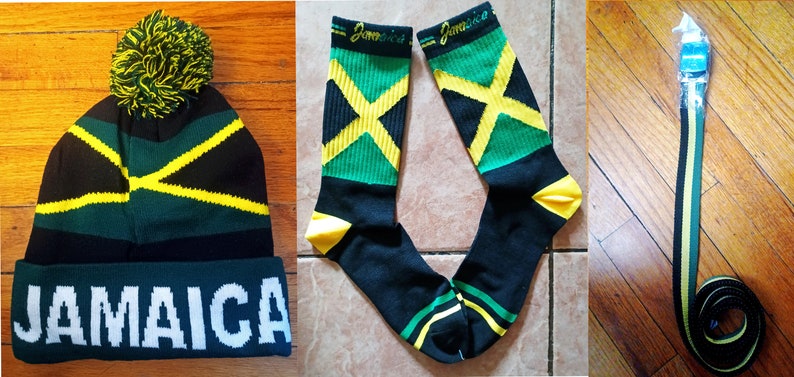 May include: A set of three Jamaican themed accessories: a black, green, and yellow beanie with a pom-pom, a pair of black socks with a green, yellow, and black Jamaican flag design, and a black, green, and yellow belt.