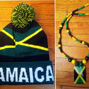 May include: A black, green, and yellow knit beanie with a pom-pom on top and the word "JAMAICA" written in white on the cuff. A black, green, and yellow beaded necklace with a rectangular pendant featuring the Jamaican flag.
