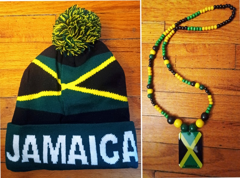 May include: A black, green, and yellow knit beanie with a pom-pom on top and the word "JAMAICA" written in white on the cuff. A black, green, and yellow beaded necklace with a rectangular pendant featuring the Jamaican flag.