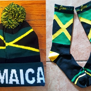 May include: A black, green, and yellow knit beanie with a pom pom on top and the word "JAMAICA" written in white on the brim. A pair of black, green, and yellow socks with the word "Jamaica" written on the top of each sock.