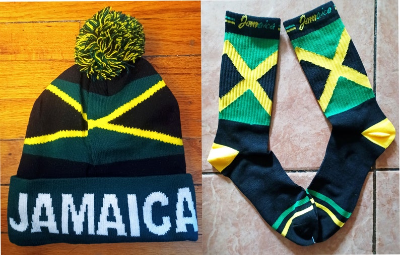 May include: A black, green, and yellow knit beanie with a pom pom on top and the word "JAMAICA" written in white on the brim. A pair of black, green, and yellow socks with the word "Jamaica" written on the top of each sock.