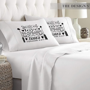 May include: Two white pillowcases with black text and arrows. The text on the pillowcases reads "With his love he will calm all your fears - Zephaniah 3:17" and "With his love he will calm all your fears - Isaiah 3:17".