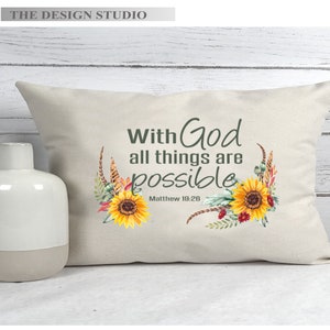 Pu&ograve; includere: Un cuscino bianco con il testo "With God all things are possible" e il riferimento biblico "Matthew 19:26". Il cuscino &egrave; decorato con un motivo floreale con girasoli e fiori rossi.