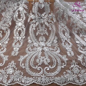 K&ouml;nnte beinhalten: Wei&szlig;er Spitzenstoff mit einem zarten Blumenmuster. Die Spitze hat einen dezenten Schimmer und ist perfekt, um jedem Projekt einen Hauch von Eleganz zu verleihen.