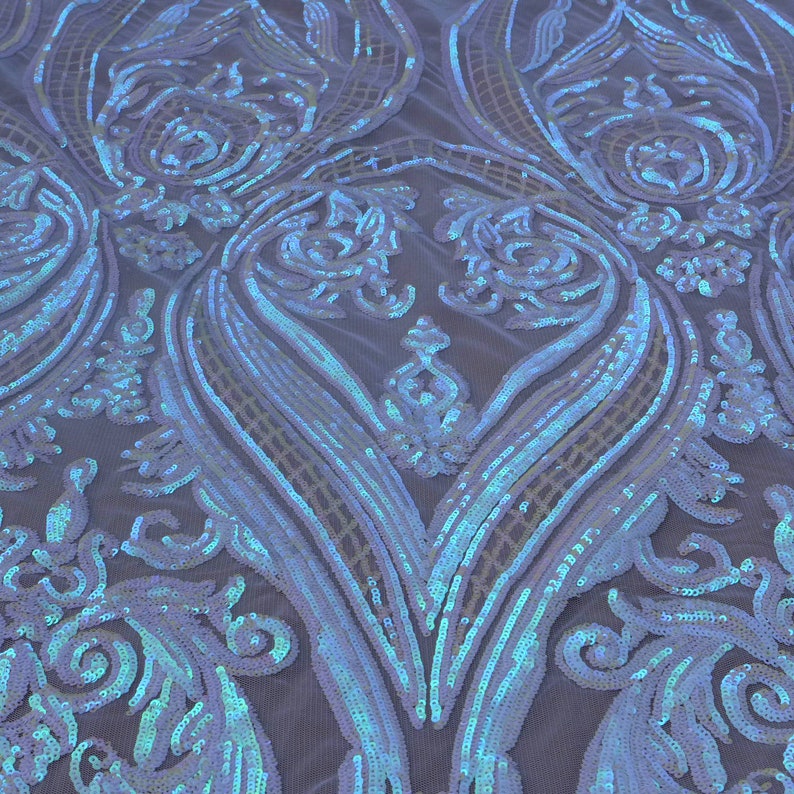 May include: White iridescent sequins on a mesh fabric with a damask pattern. The sequins are a light blue color with a shimmery finish.