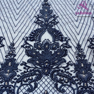 May include: Navy blue beaded lace fabric with a floral design. The fabric has a geometric pattern and is embellished with small beads and rhinestones.