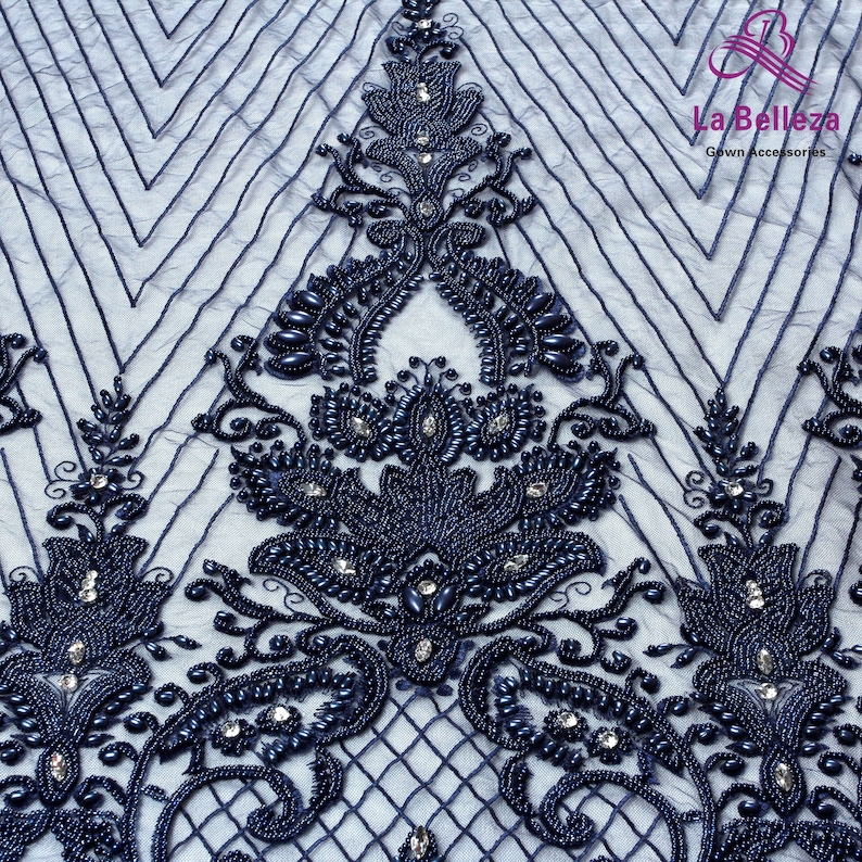 May include: Navy blue beaded lace fabric with a floral design. The fabric has a geometric pattern and is embellished with small beads and rhinestones.