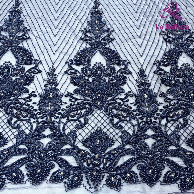 May include: Navy blue beaded lace fabric with a floral design. The fabric has a delicate, intricate pattern with small beads and sequins.