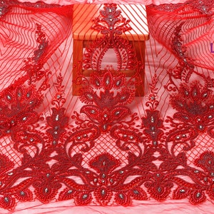 May include: Red beaded lace fabric with a floral design. The fabric is sheer and has a delicate texture. The beads are small and evenly spaced. The fabric is perfect for making dresses, skirts, and other garments.