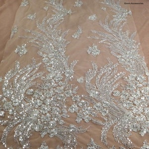 May include: Silver sequined fabric with a floral pattern on a sheer beige mesh background. La Belleza Gown Accessories.