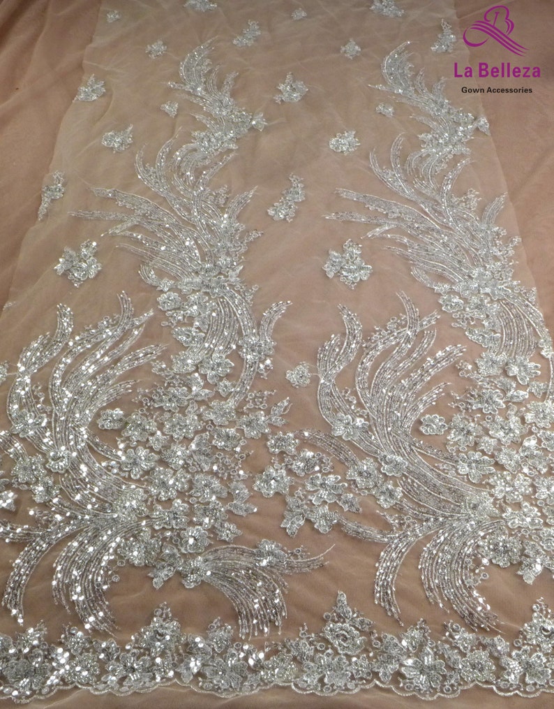 May include: Silver sequined fabric with a floral pattern on a sheer beige mesh background. La Belleza Gown Accessories.