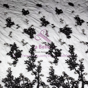 May include: Black beaded lace fabric featuring floral patterns and small, clear rhinestones. The fabric is sheer and delicate, with a soft, flowing texture.