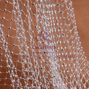 May include: White mesh fabric with small, clear rhinestones. The fabric is woven in a net-like pattern.
