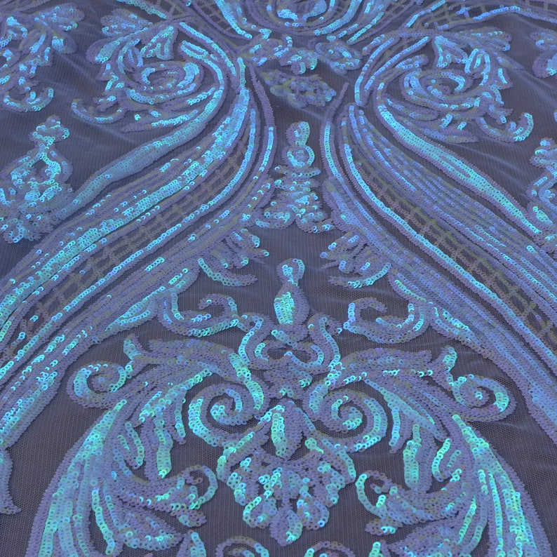 May include: A close-up of iridescent blue and white sequined fabric with a damask pattern. The sequins are sewn onto a sheer mesh backing.