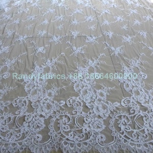 May include: White lace fabric with a delicate floral pattern. The lace is soft and sheer, and it would be perfect for a variety of projects, such as wedding dresses, tablecloths, and curtains.