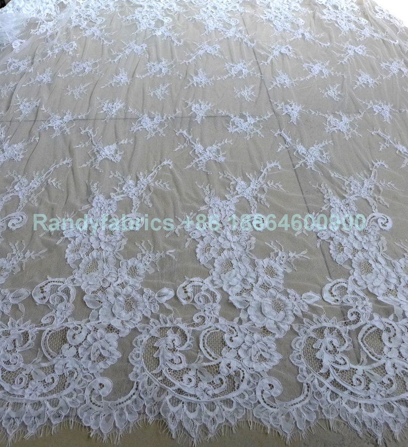 May include: White lace fabric with a delicate floral pattern. The lace is soft and sheer, and it would be perfect for a variety of projects, such as wedding dresses, tablecloths, and curtains.