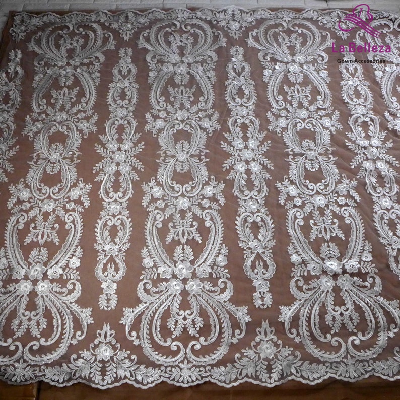 K&ouml;nnte beinhalten: Wei&szlig;er, gestickter Spitzenstoff mit einem Blumenmuster. Der Stoff hat ein zartes, filigranes Design mit kleinen Blumen und Bl&auml;ttern.