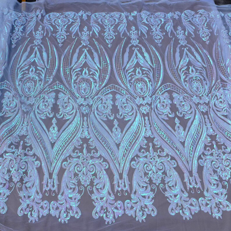 May include: Pale blue iridescent sequin fabric with a damask pattern. The sequins are arranged in a repeating design of swirls and leaves.