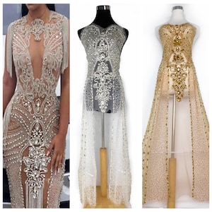 Può includere: Due applicazioni in tessuto perlato, una in argento e una in oro, sono esposte su manichini. Le applicazioni sono realizzate in un tessuto trasparente con un motivo perlato. Le applicazioni sono perfette per aggiungere un tocco di brillantezza a qualsiasi capo.