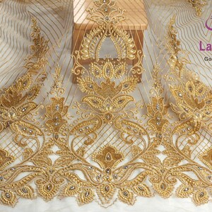 May include: Gold beaded lace fabric with a delicate floral pattern. The fabric is sheer and has a subtle shimmer. It is perfect for adding a touch of elegance to any project.