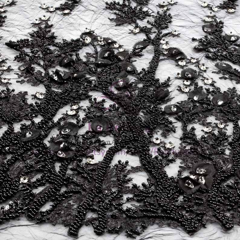 May include: Black beaded lace fabric with a floral design. The fabric is embellished with small black beads and clear rhinestones.