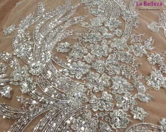 Könnte beinhalten: Silberner Paillettenstoff mit floralem Muster auf einem durchsichtigen beigefarbenen Netzstoff. La Belleza Gown Accessories ist in der oberen rechten Ecke gedruckt.