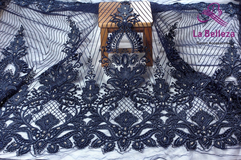 May include: Navy blue beaded lace fabric with a floral design. The fabric is sheer and has a delicate texture. The beads are small and evenly spaced.