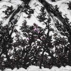 May include: Black beaded lace fabric with a floral design. The fabric is made of a sheer mesh with black beads and sequins.