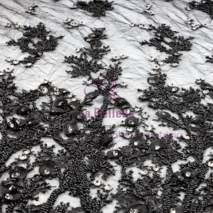 May include: Black beaded lace fabric with a floral design and clear rhinestones. The fabric is sheer and has a delicate texture.