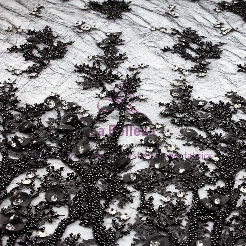 May include: Black beaded lace fabric with a floral design and clear rhinestones. The fabric is sheer and has a delicate texture.
