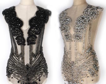 May include: Two beaded embellishments for clothing, one black and one silver. Both are made of rhinestones and beads, and are designed to be sewn onto a garment. The embellishments are displayed on mannequins.