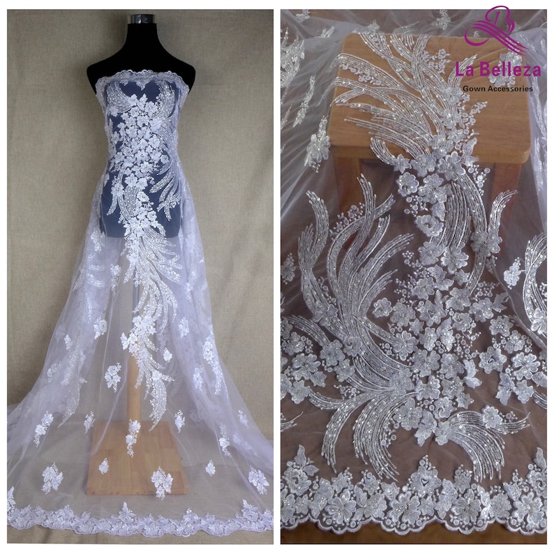 May include: White beaded lace fabric with a floral design. The fabric is sheer and has a delicate, feminine look. It is perfect for adding a touch of elegance to any project.