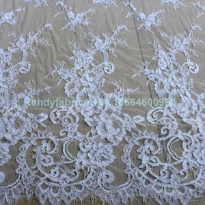 May include: White lace fabric with a delicate floral pattern. The lace is sheer and has a soft, flowing texture.