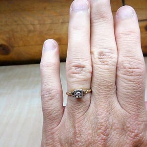 May include: A gold ring with a square-shaped diamond set in the center.