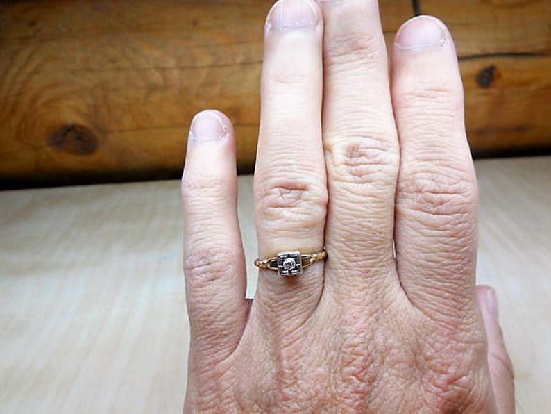 May include: A gold ring with a square-shaped diamond set in the center.