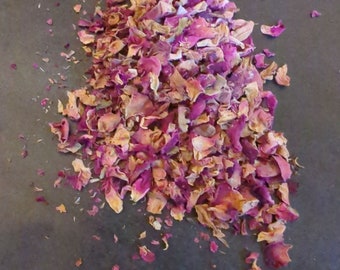 Puede incluir: Una colección de pétalos de flores secas en tonos magenta vibrante, rosa suave y crema apagado. Las pequeñas piezas botánicas fragmentadas están agrupadas, mostrando texturas variadas y formas irregulares debido al proceso de secado.