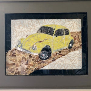 May include: A yellow mosaic art piece depicting a vintage Volkswagen Beetle driving on a mosaic road.