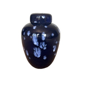 May include: A dark blue ceramic jar with a white speckled design. The jar has a lid and is a decorative piece.