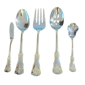 May include: A set of five silver-colored serving utensils. The set includes a butter knife, a spoon, a fork, a slotted spoon, and a small spoon. Each piece has a decorative floral design on the handle.