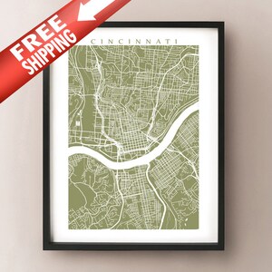 May include: A framed map print of Cincinnati, Ohio, in a minimalist style. The map features white street lines on an olive green background, with the city name at the top. The print is in a black frame.