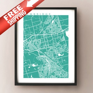 Op de afbeelding: Een ingelijste teal en witte kaartprint van Cambridge. De kaart toont een gedetailleerde stratenkaart op een teal achtergrond. De print zit in een zwart frame en heeft het woord "Cambridge" bovenaan. Een rode banner met de tekst "FREE SHIPPING" staat linksboven.