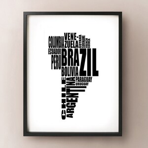 May include: Black framed print featuring a stylized map of South America. The continent's shape is formed by the names of its countries in black text against a white background. The word "Brazil" is prominently displayed.